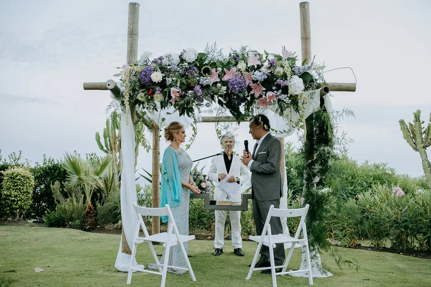 Novia, novio y oficiante bajo el arco de flores, Tikitano