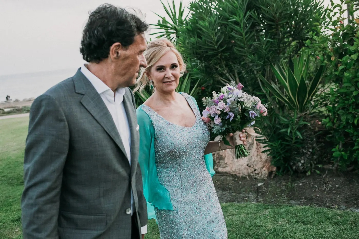 El novio mira a la novia entre las palmeras y los agaves del jardín
