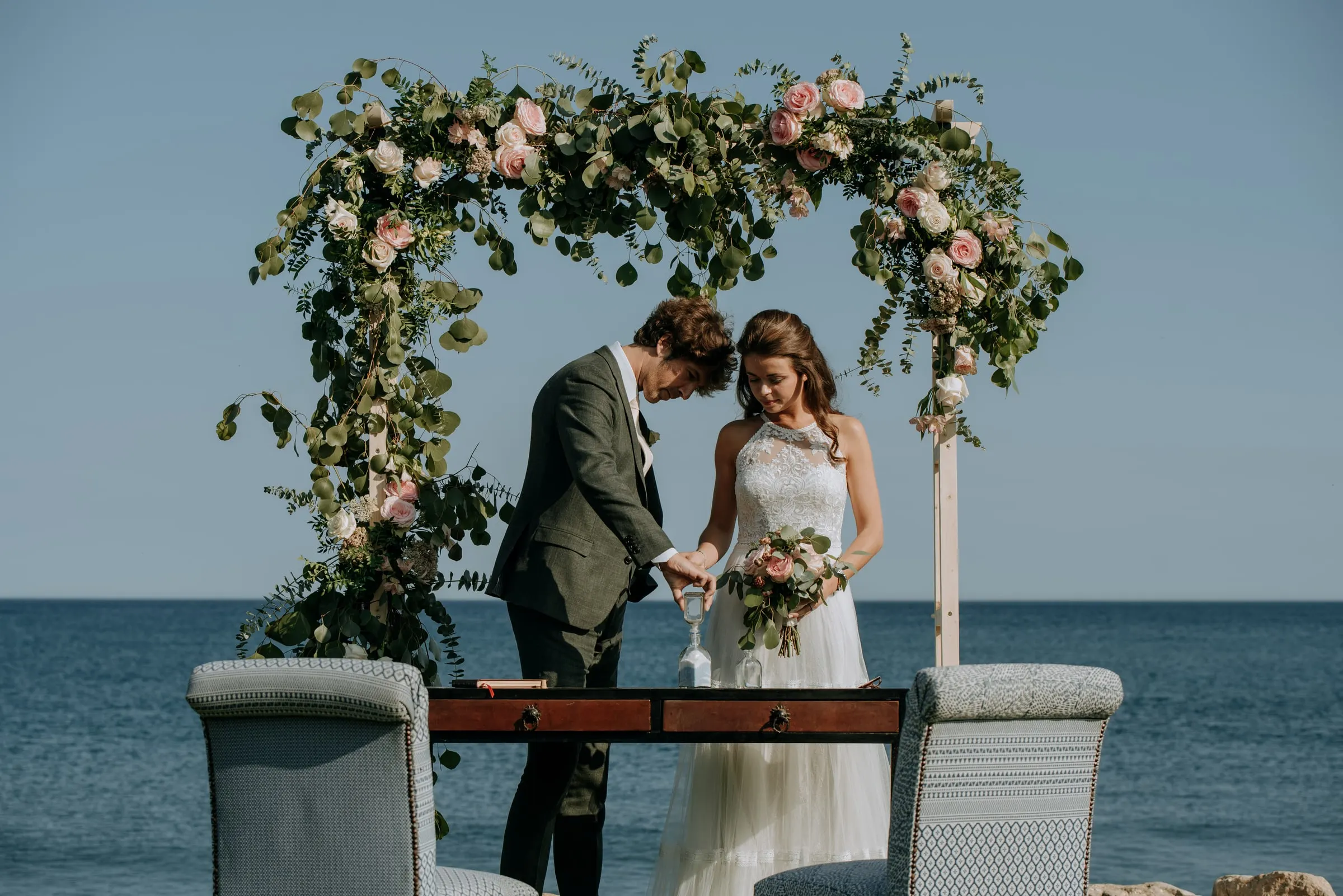 Los novios firman en la mesa de ceremonia bajo el arco floral frente al mar, Trocadero, Sotogrande
