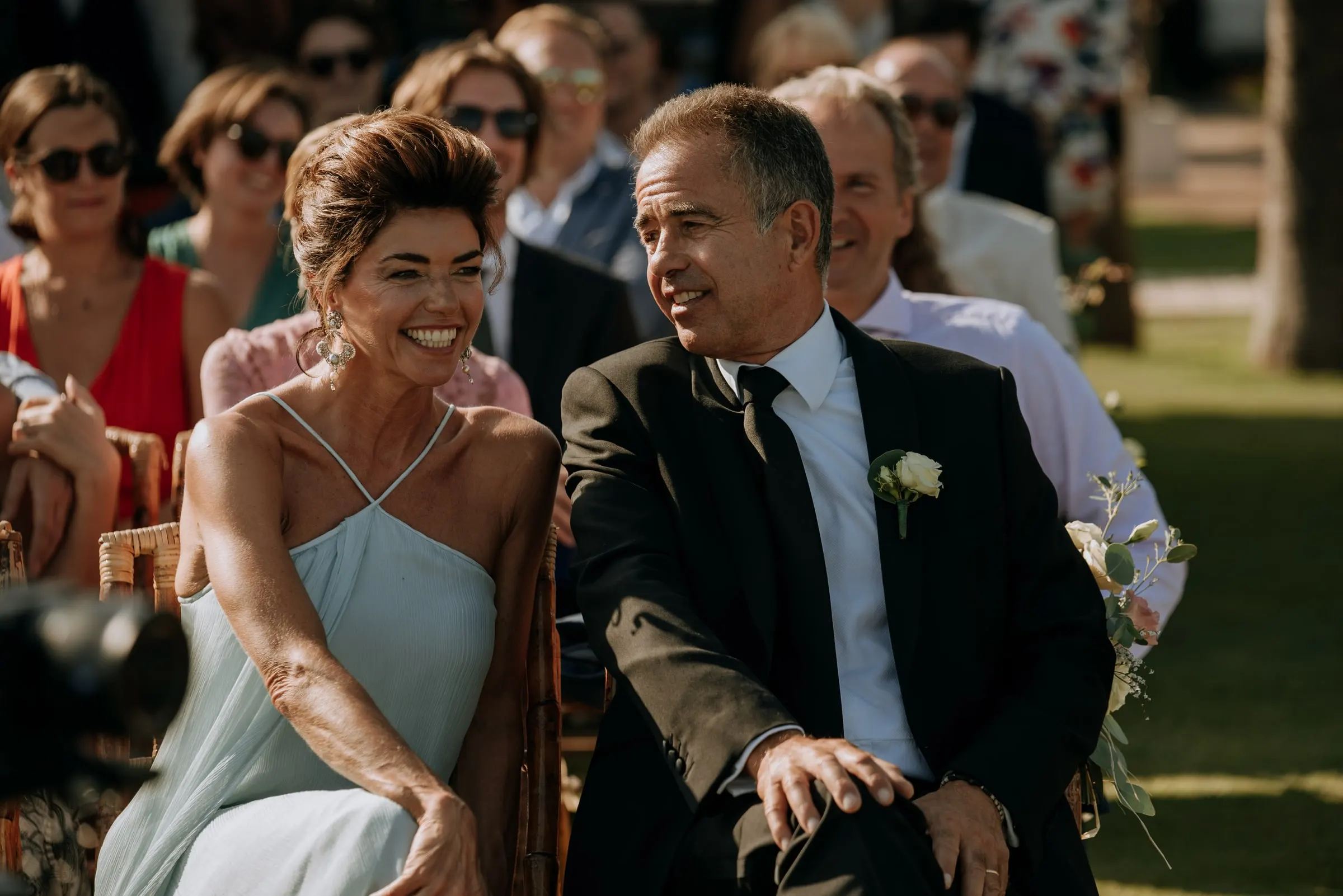 Una pareja de invitados sonríe mientras sigue la ceremonia al aire libre, Trocadero, Sotogrande