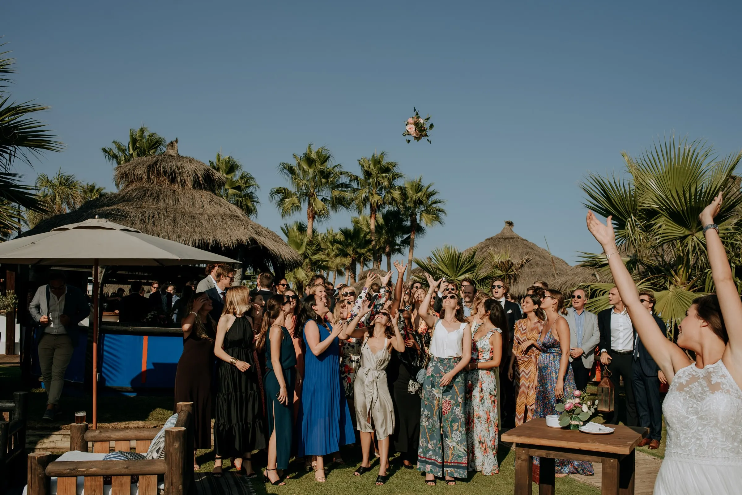 La novia lanza el ramo a un grupo de invitados entre palmeras, Trocadero, Sotogrande