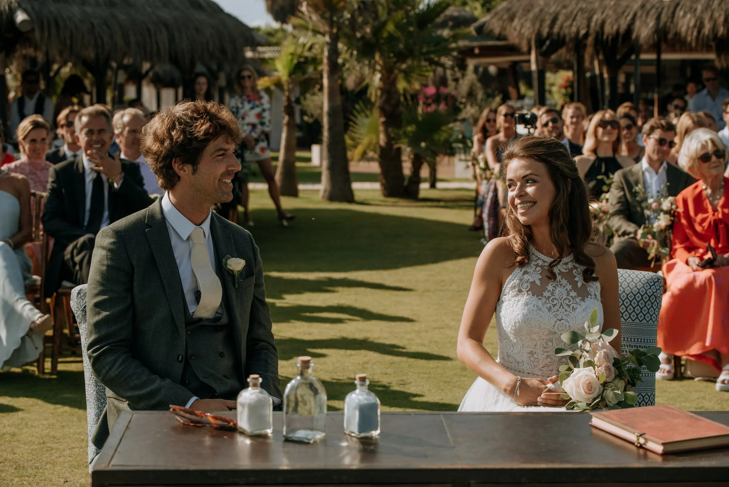 Los novios, sentados en la mesa de ceremonia, se sonríen, Trocadero, Sotogrande