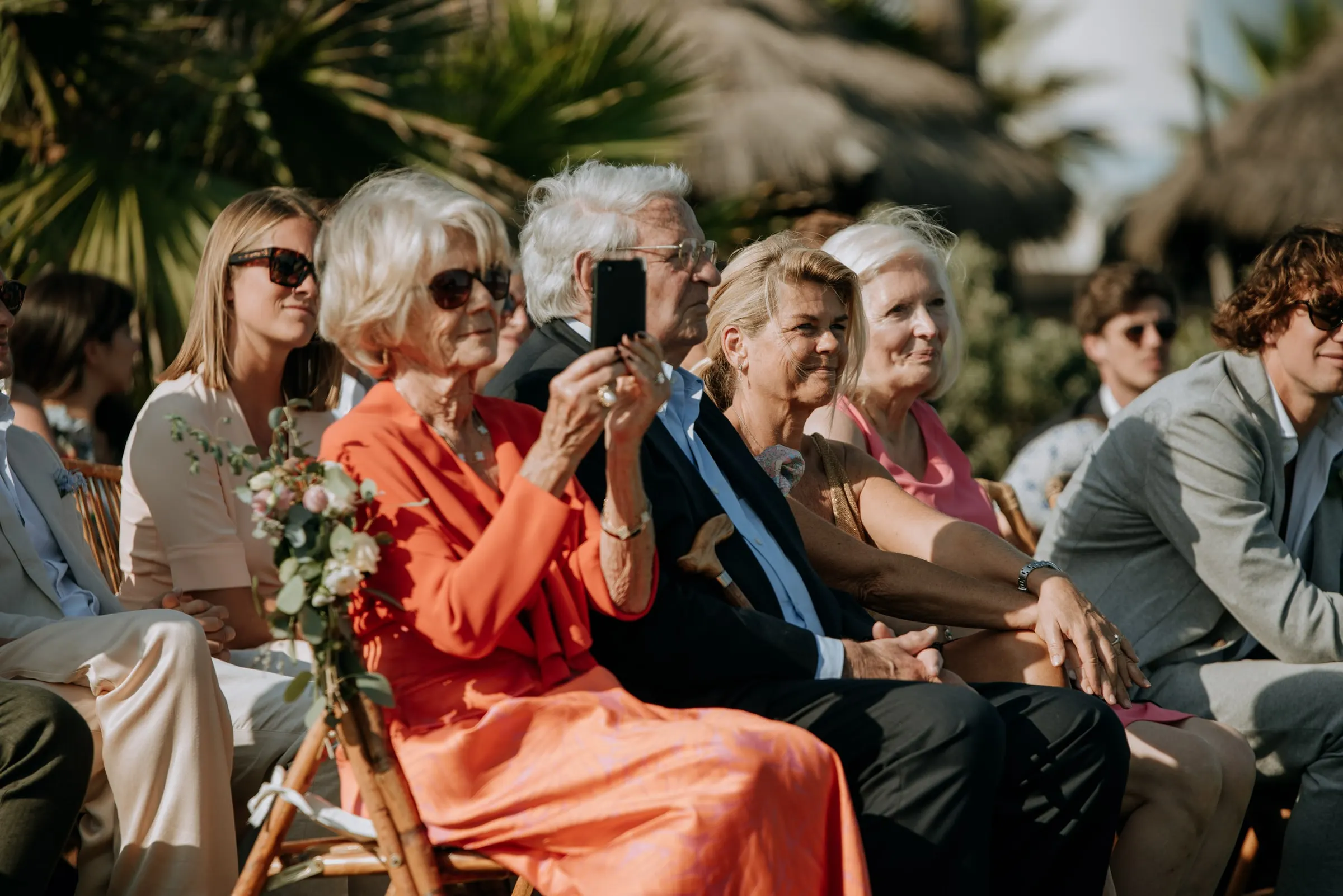 Invitados de las primeras filas sonríen y una mujer graba la ceremonia con el móvil, Trocadero, Sotogrande