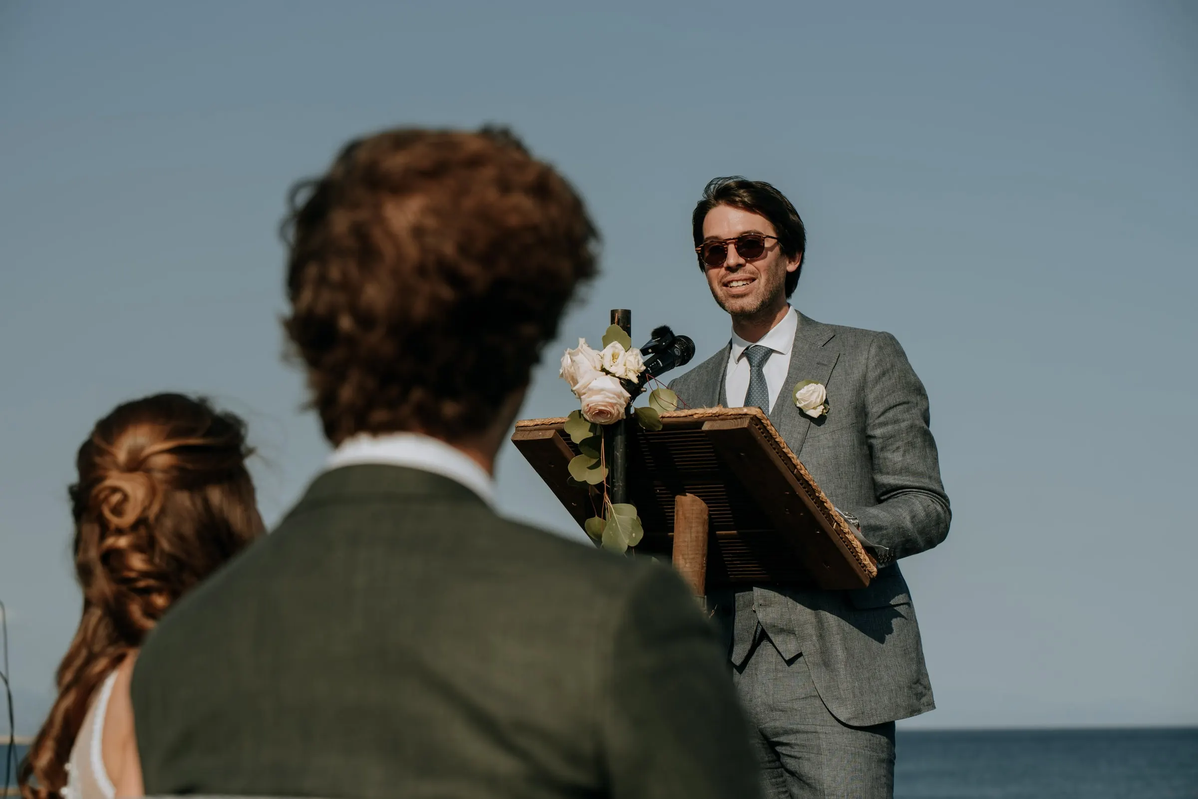 El oficiante sonríe en el atril, visto por encima de los hombros de los novios, Trocadero, Sotogrande