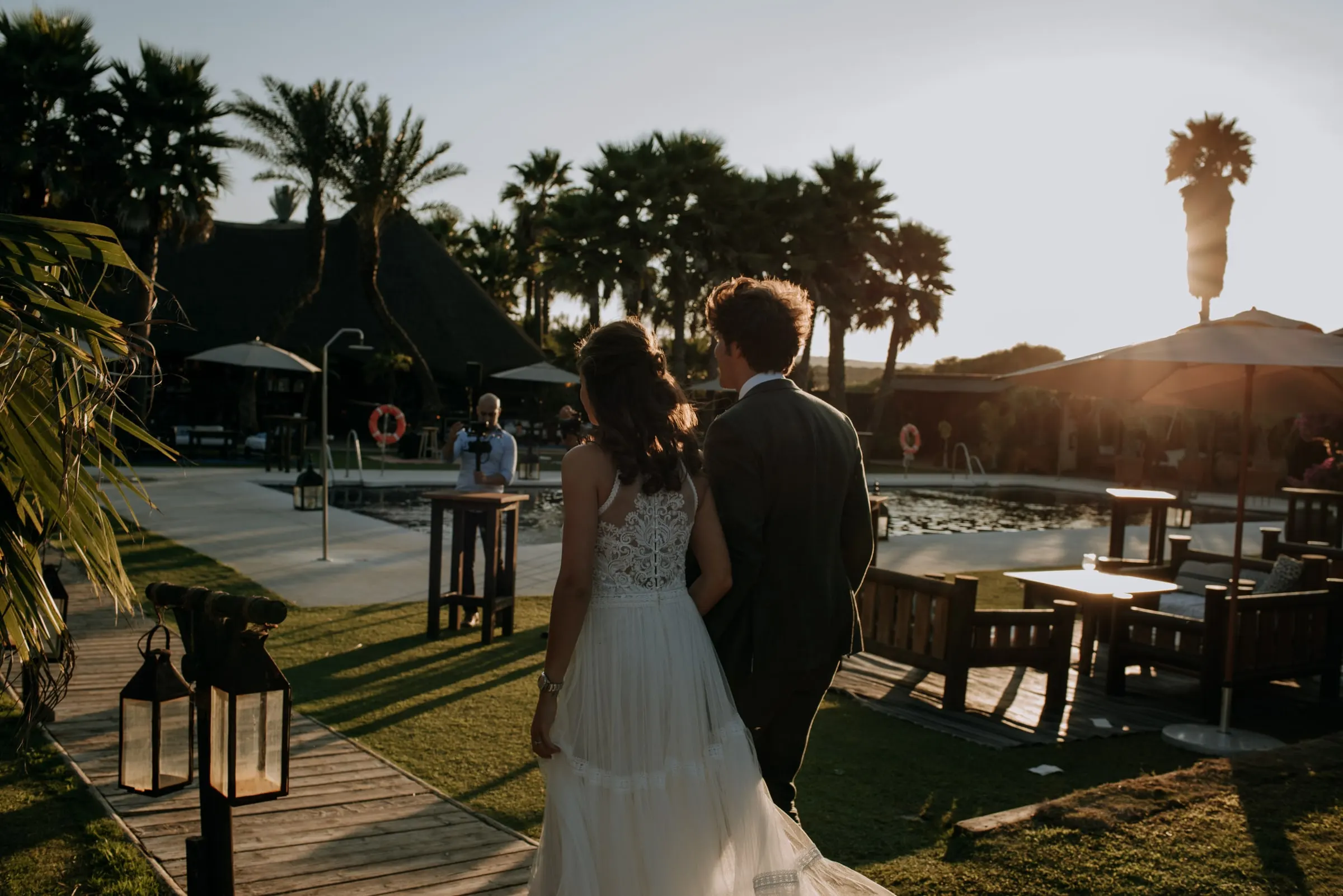 Los novios, de espaldas, caminan hacia la piscina al atardecer, Trocadero, Sotogrande