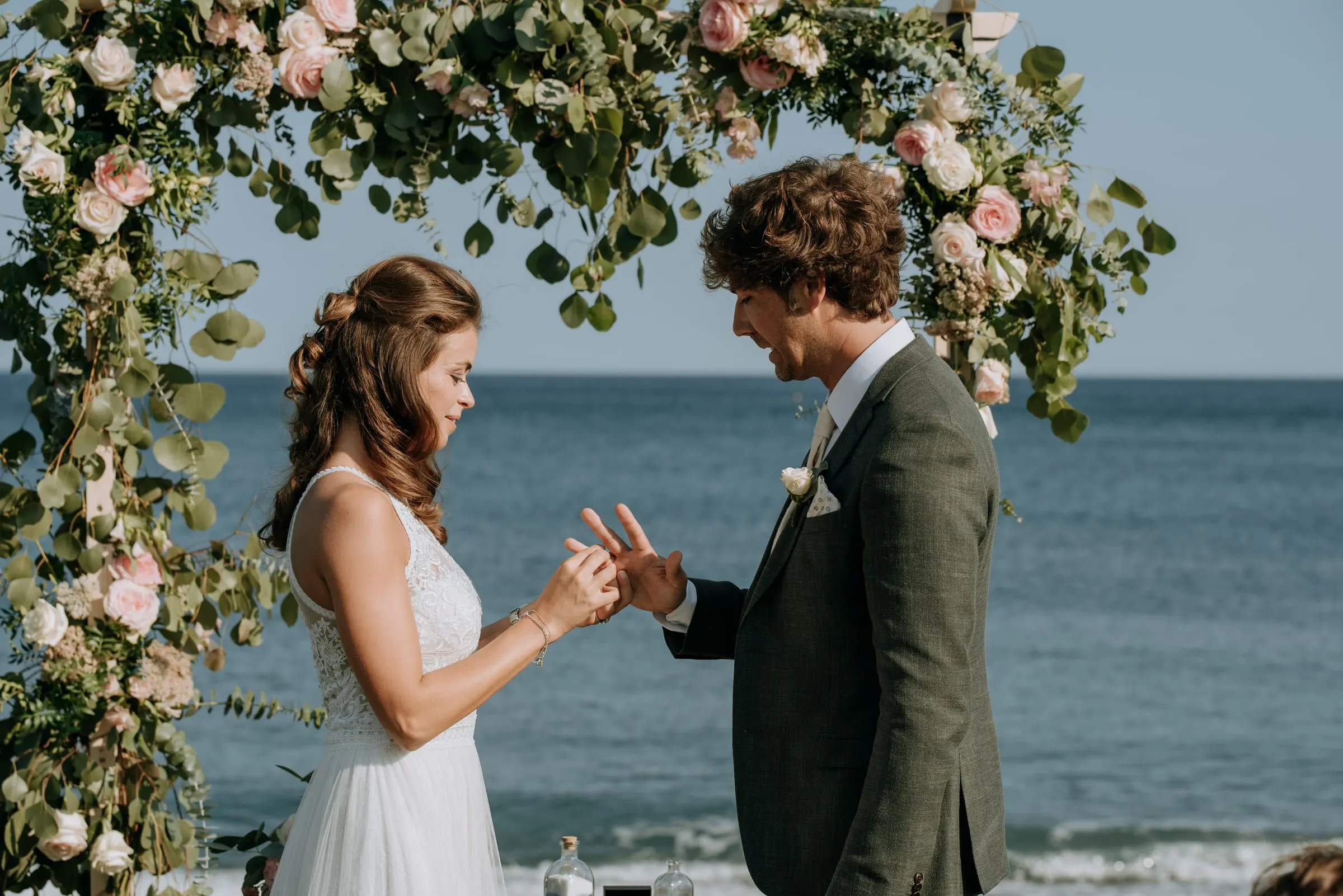 La novia pone el anillo al novio bajo el arco de flores, Trocadero, Sotogrande