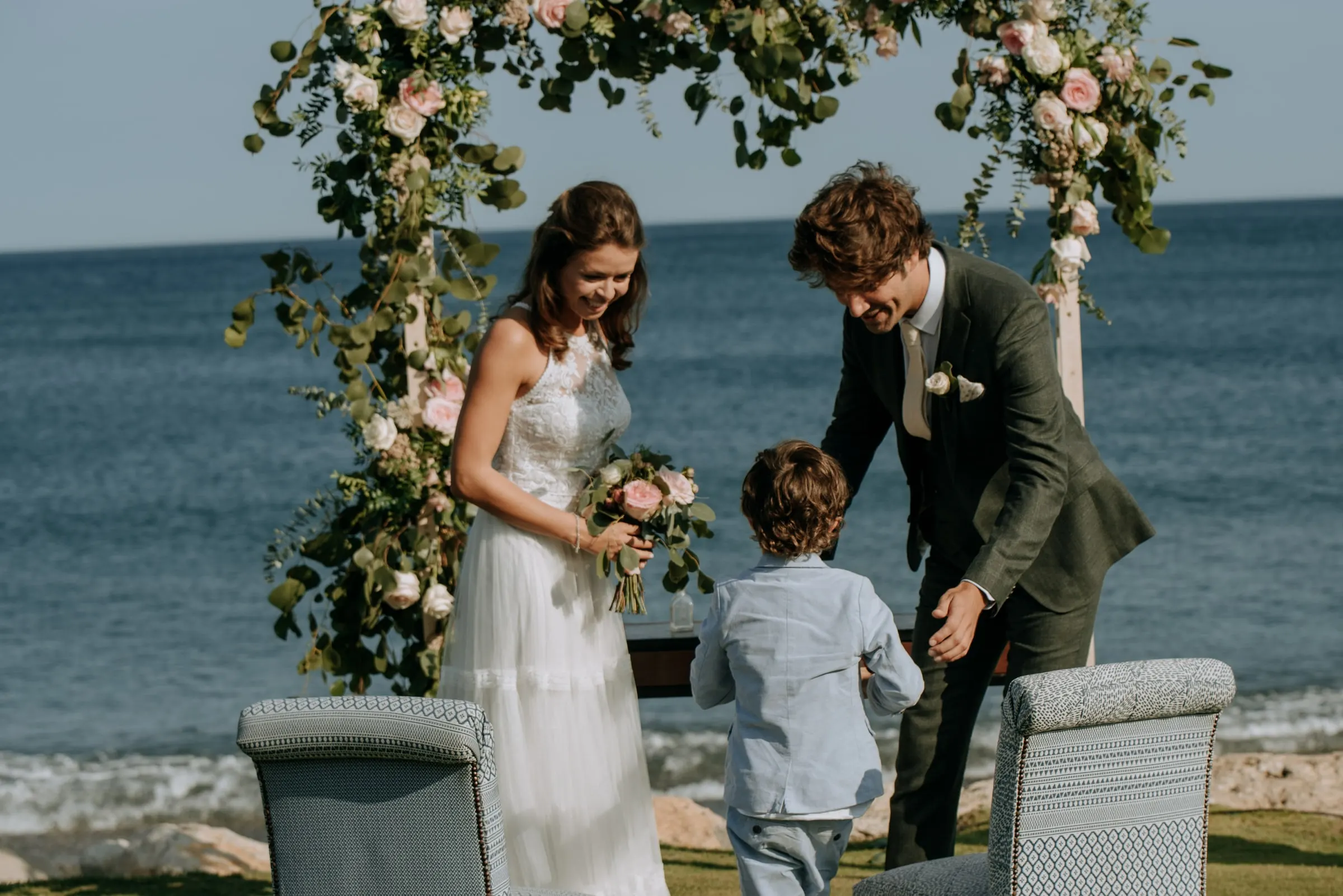 Un niño lleva los anillos a los novios bajo el arco de flores, Trocadero, Sotogrande
