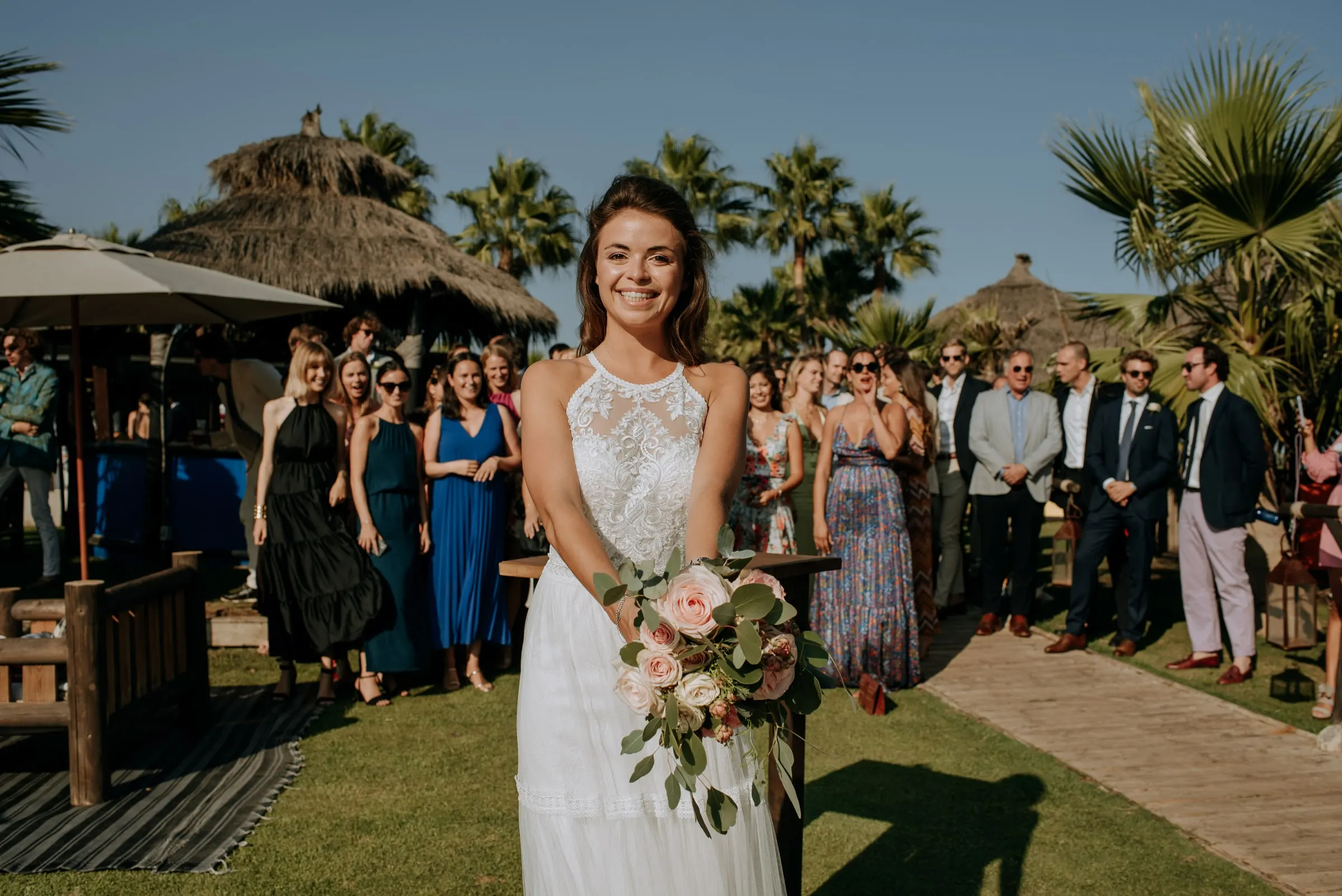 La novia sonríe con el ramo antes de lanzarlo, con los invitados esperando detrás, Trocadero, Sotogrande