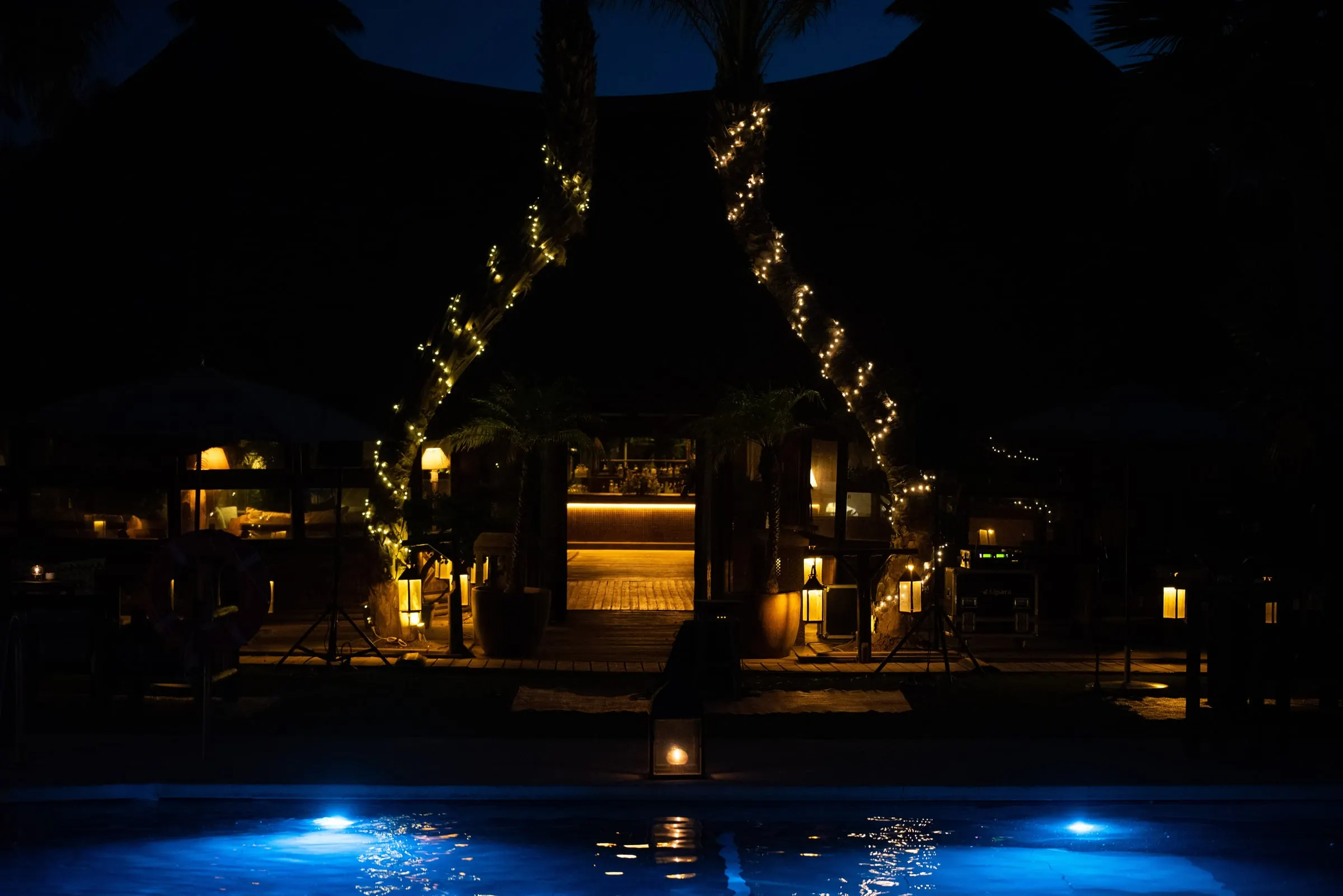 La piscina iluminada de azul por la noche con guirnaldas de luces entre palmeras, Trocadero, Sotogrande