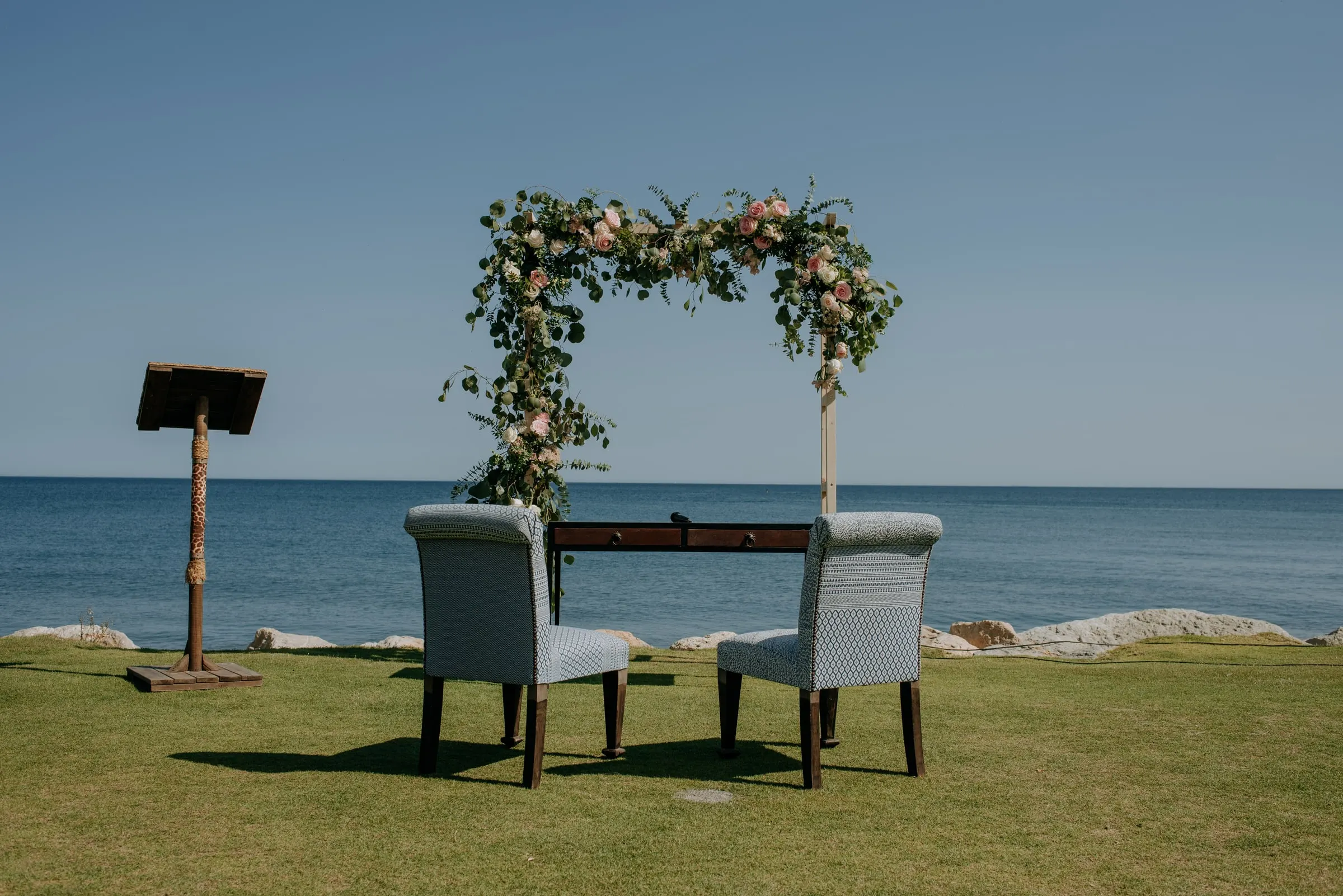 El espacio de ceremonia vacío: arco floral, dos sillones y un atril frente al mar, Trocadero, Sotogrande