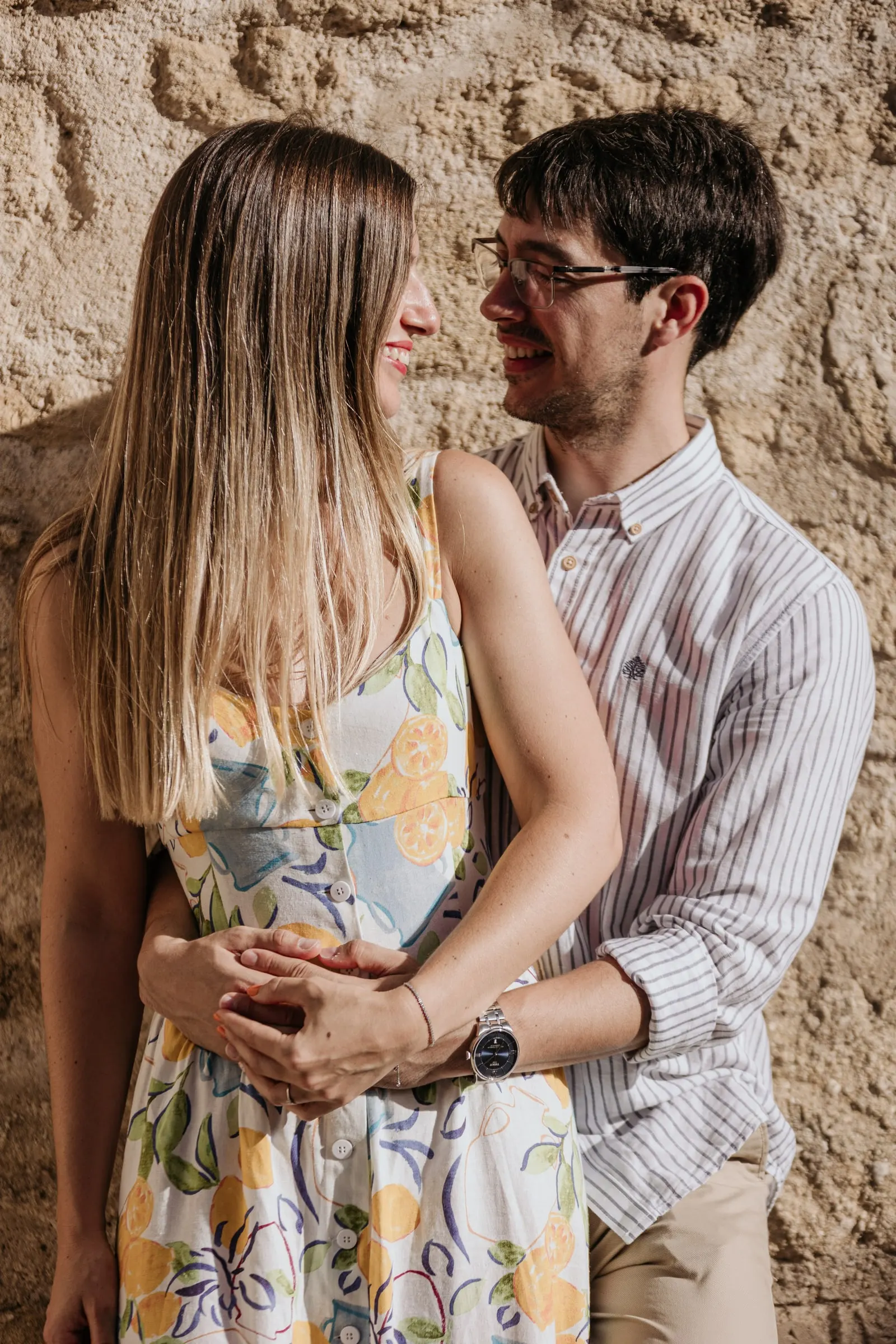 La pareja mejilla con mejilla sobre la piedra dorada del casco antiguo de Vejer