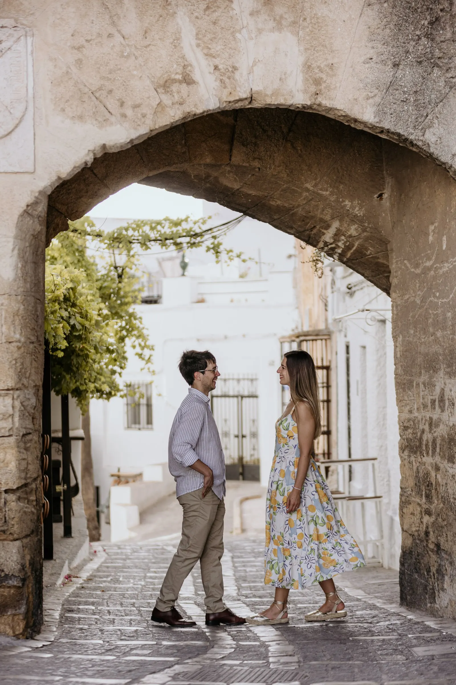 La pareja frente a frente en la calle, vista a través de un arco de piedra oscuro, Vejer de la Frontera