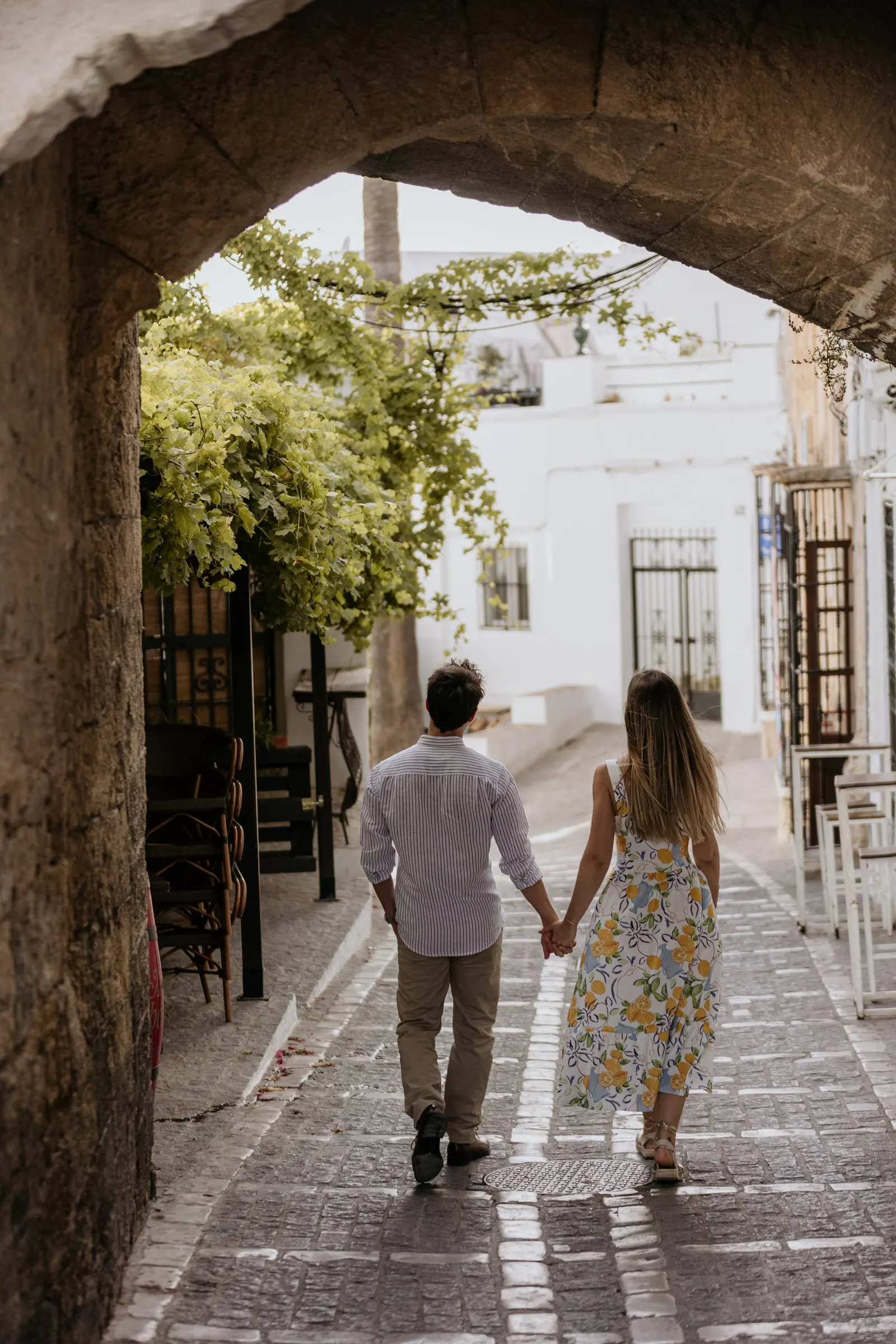 La pareja se aleja de la mano por un arco hacia las calles blancas de Vejer