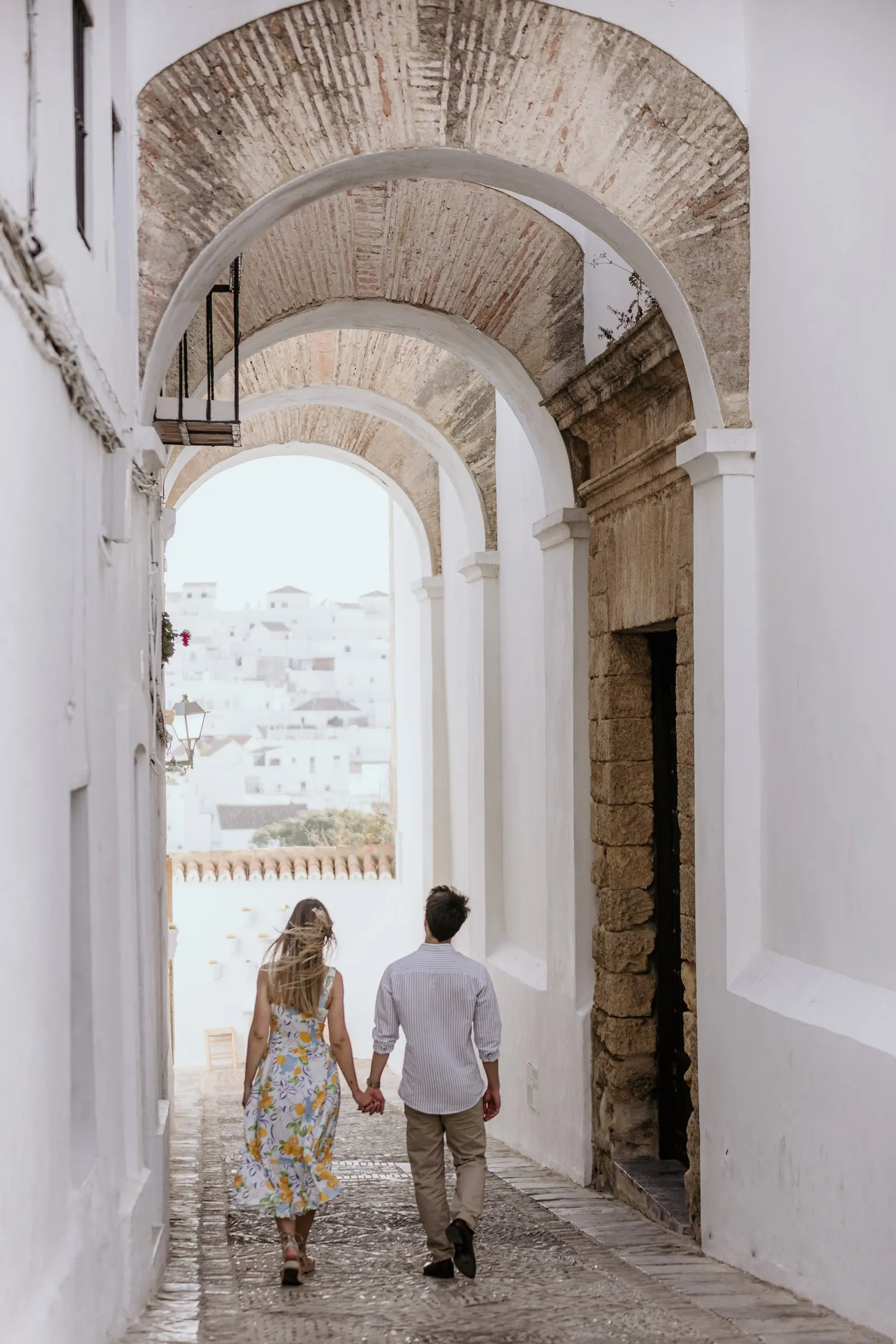 La pareja camina bajo los arcos encalados de una calle estrecha de Vejer