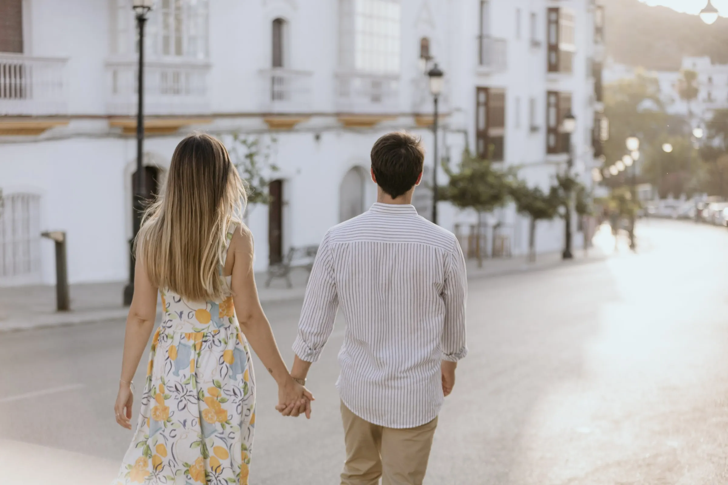 La pareja pasea de la mano junto a casas blancas y farolas en Vejer