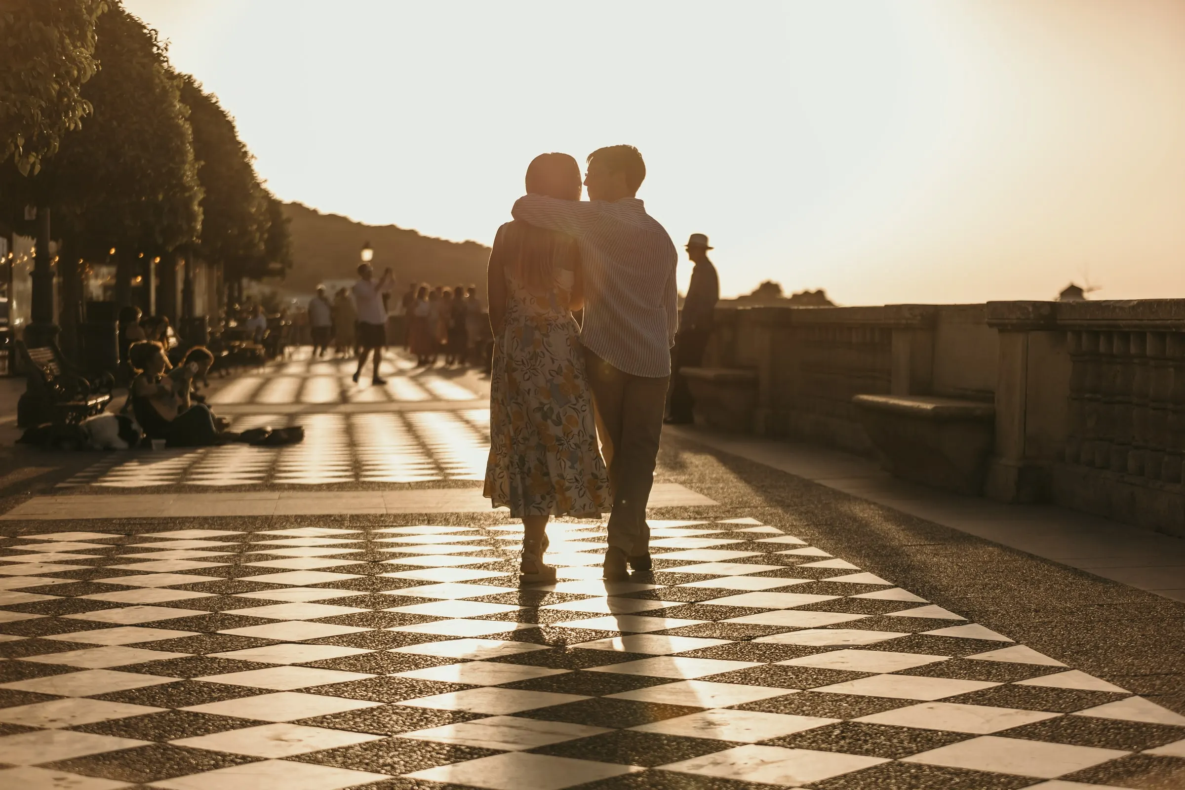 La pareja pasea al atardecer por un paseo ajedrezado bajo los árboles en Vejer
