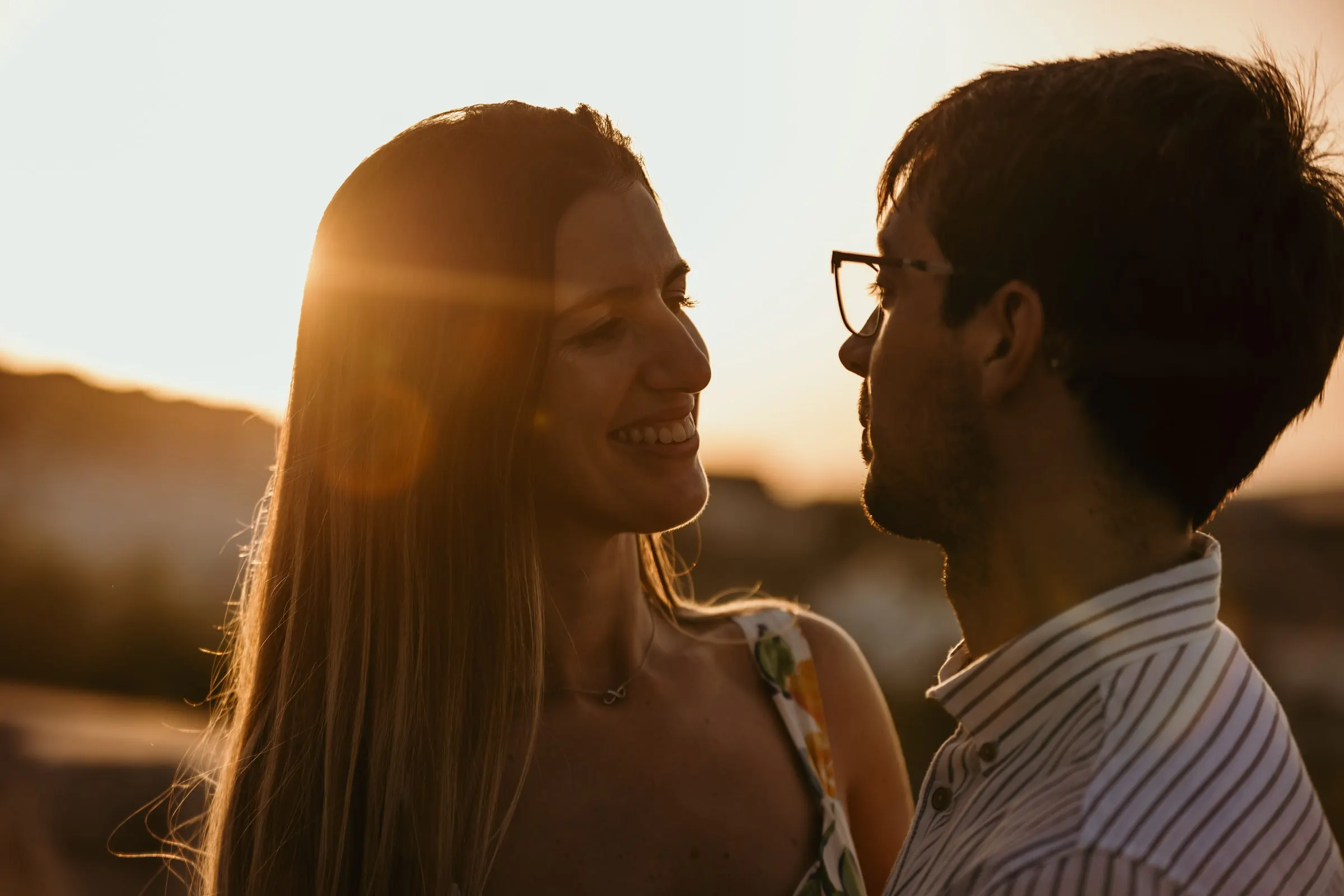 La pareja ríe frente a frente con el sol poniente destellando entre ellos, Vejer