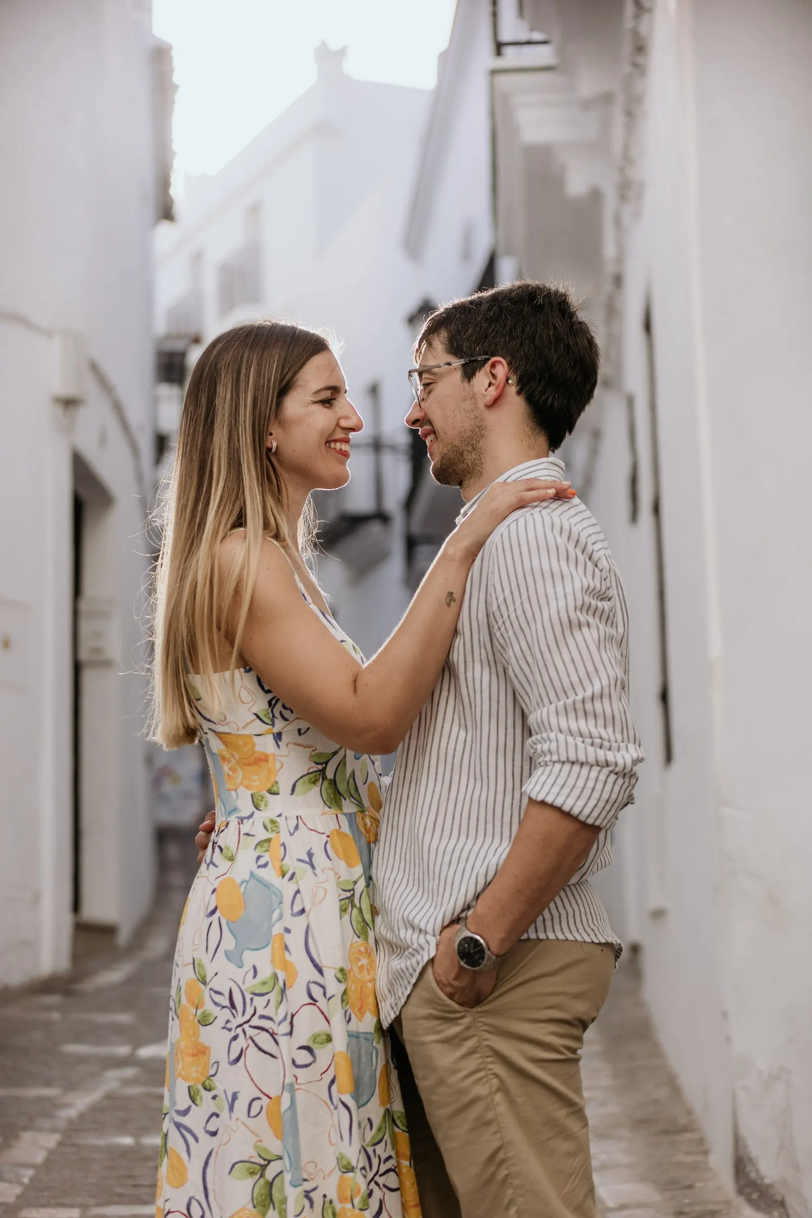 La futura novia con la mano en el pecho de su prometido en una calle encalada y estrecha de Vejer