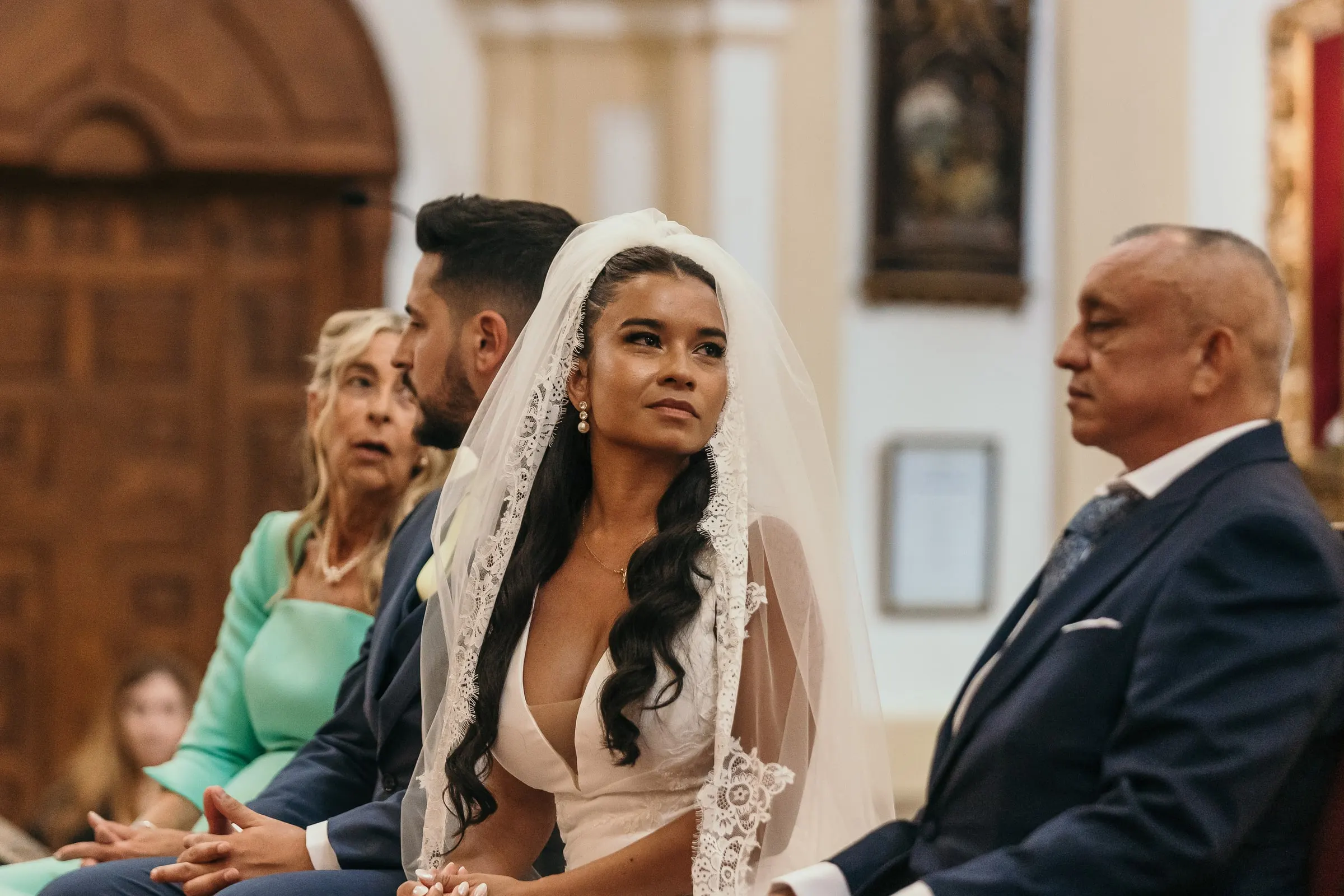 La novia sentada junto al novio durante la ceremonia, con la mirada hacia el altar