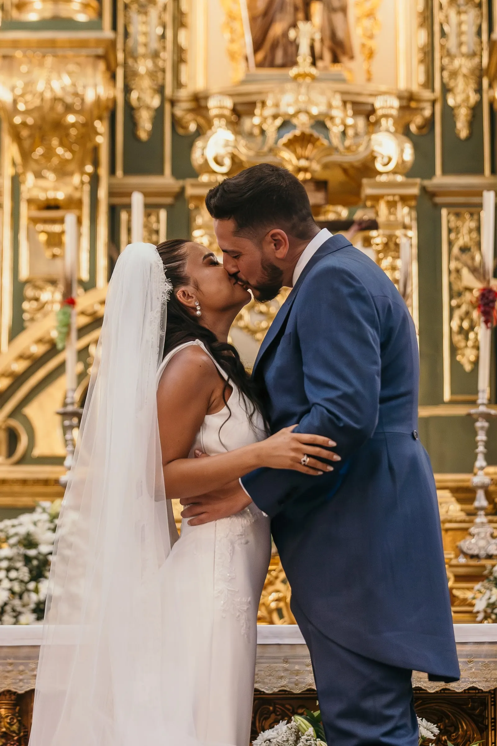 Primer beso de casados ante el retablo dorado