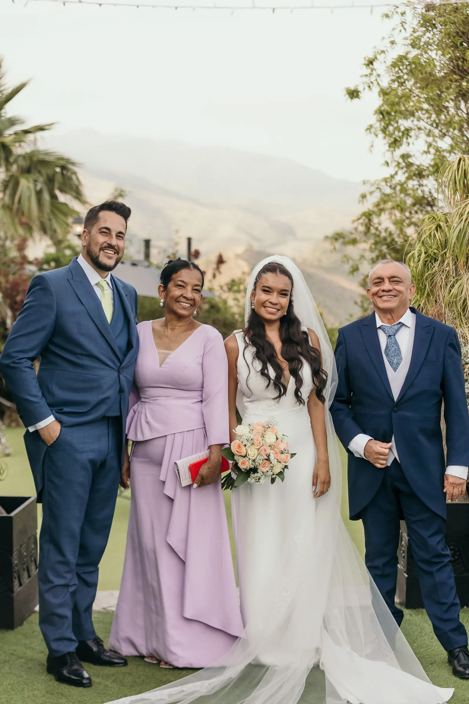 Newlyweds with the bride's parents on the lawn, hills of Marbella behind
