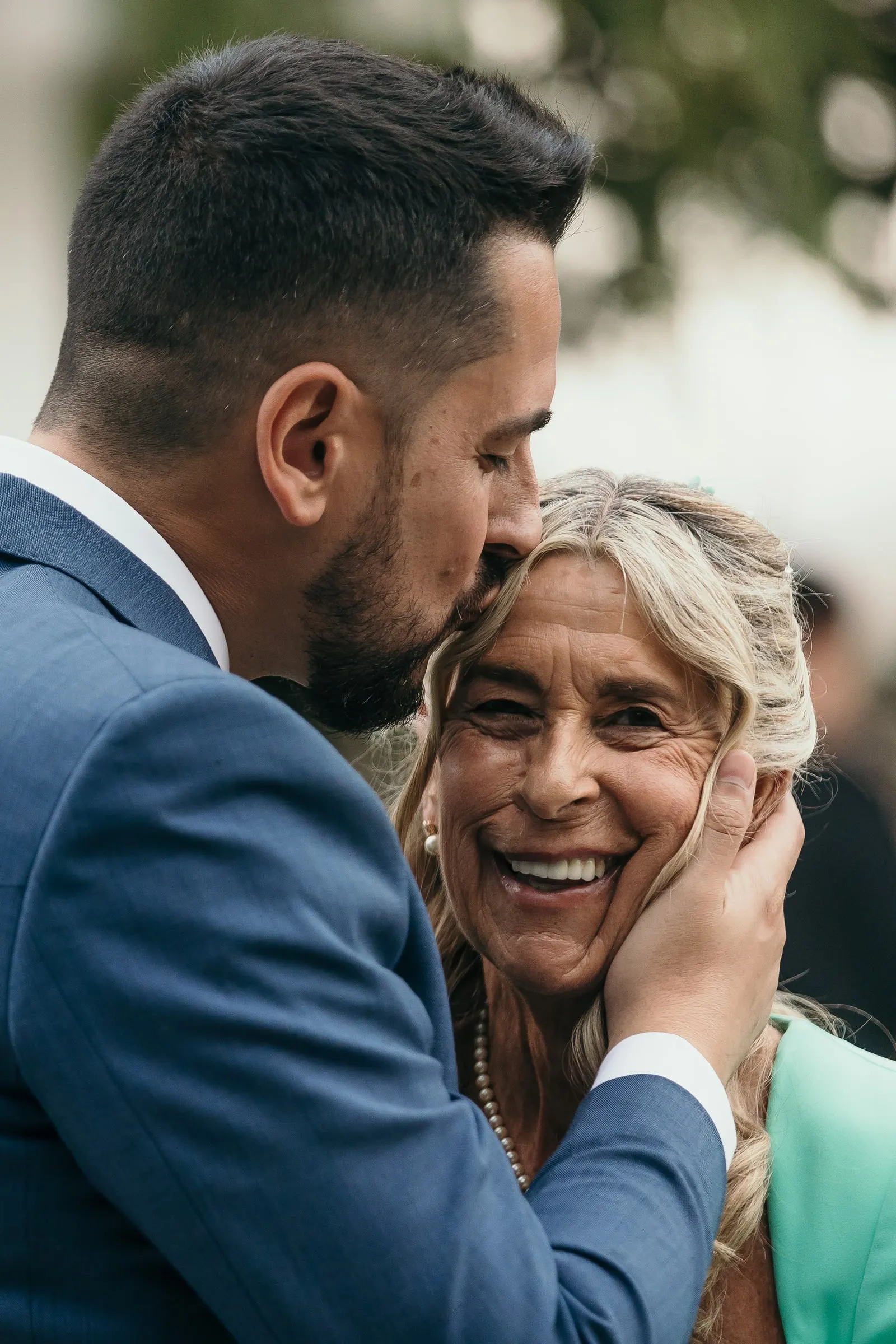 El novio besa en la frente a su madre mientras ella le sujeta la cara, boda en Marbella
